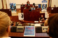 Prezydium, osoba na mównicy oraz uczestnicy konferencji.