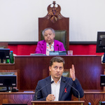 Młody mężczyzna przemawia na mównicy.