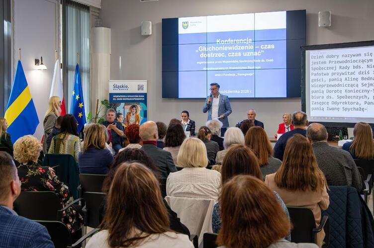 Pan Tomasz Ciesielski wita uczestników konferencji. w tle slajd z tytułem konferencji.