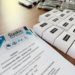 Agenda konferencji a obok leżą gadżety dla uczestników.
