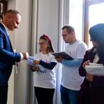 Grupa wolontariuszy z zespołem Downa wręcza ulotki uczestnikowi konferencji.